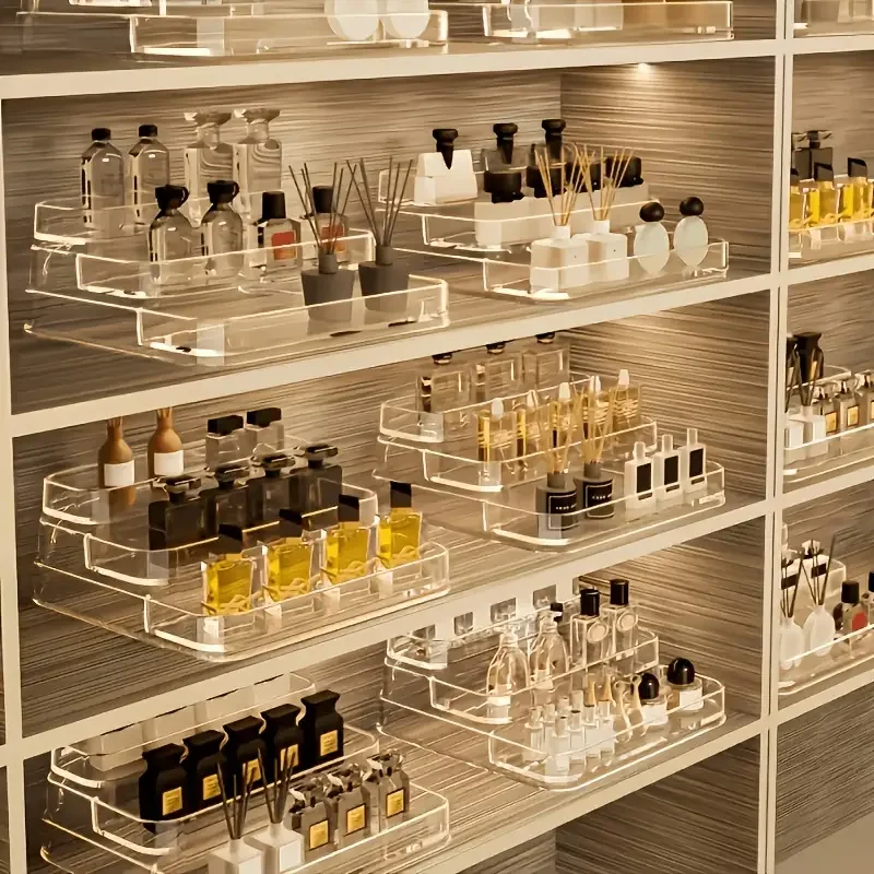 A stepped clear acrylic shelving unit holding rows of cosmetic bottles in a shop