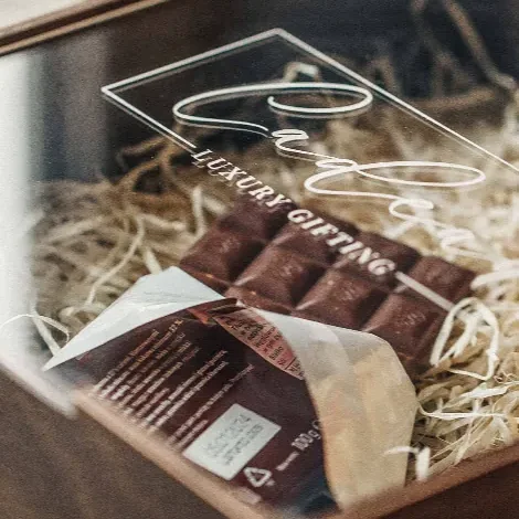 A close crop of a script wordmark engraved into the underside of a clear acrylic lid, catching the light