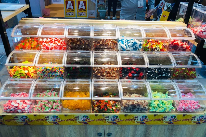 A wall of clear acrylic trays in a grid, each holding a different colored candy