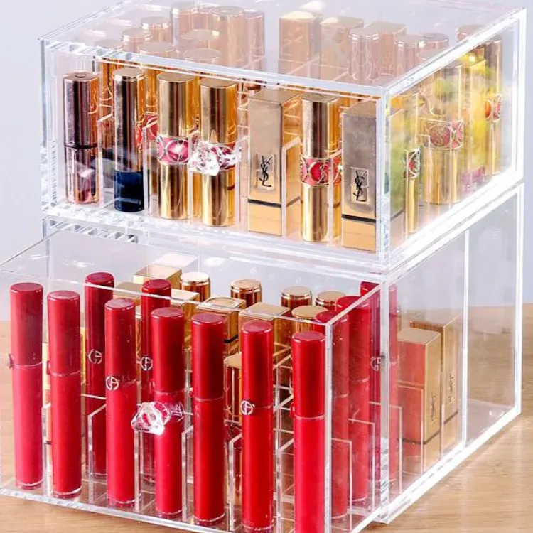 A stacked clear acrylic box with narrow divided compartments, holding slim cosmetic tubes