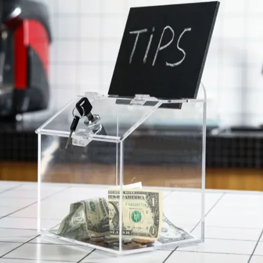 A clear acrylic collection box with a cam lock, a chalkboard sign reading TIPS and banknotes inside