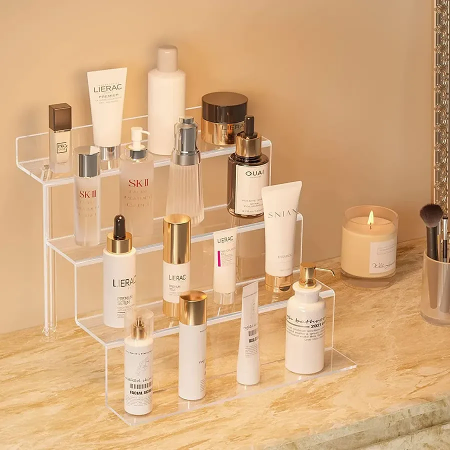 An unbranded stepped clear acrylic organizer holding cosmetic bottles and tubes