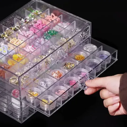 A clear acrylic drawer tower with a hand pulling one drawer open, holding small cosmetic pots
