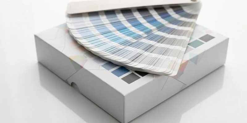 A Pantone color fan deck resting on a printed vape carton during sample approval