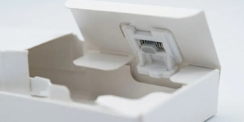 An open white child-resistant box with a press-and-slide locking mechanism