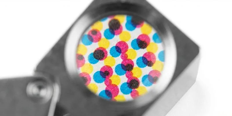 A loupe magnifying CMYK print dots on a printed carton