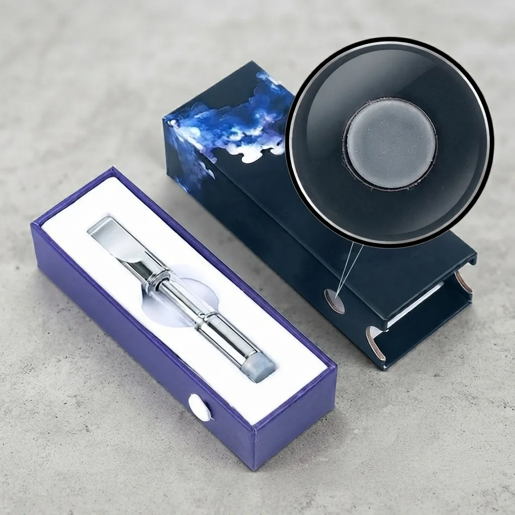 A push-and-slide box with its inner tray drawn out, holding a glass vape cartridge in a white insert, and a magnified view of the insert