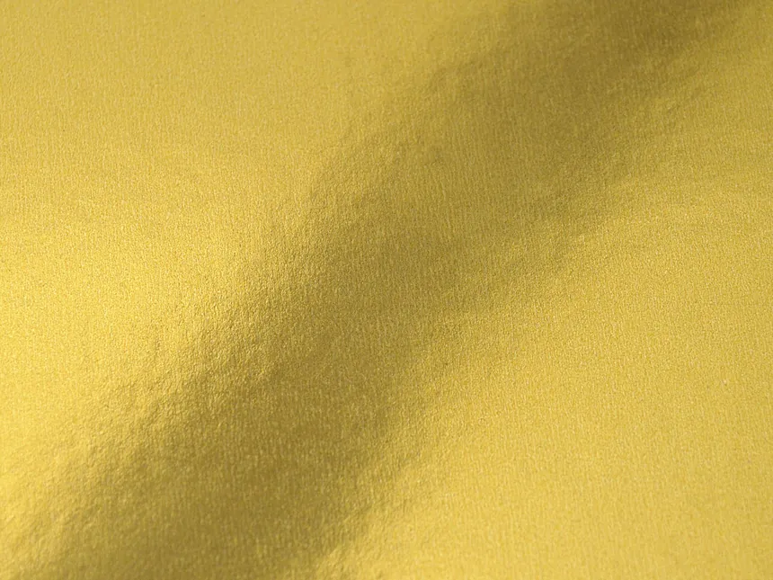 A gold foil surface reflecting a soft gradient of light