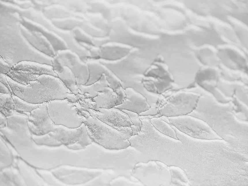 A white sheet with a floral pattern embossed into its surface