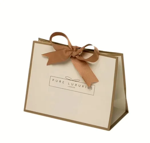 A cream gift bag tied with a wide brown ribbon bow