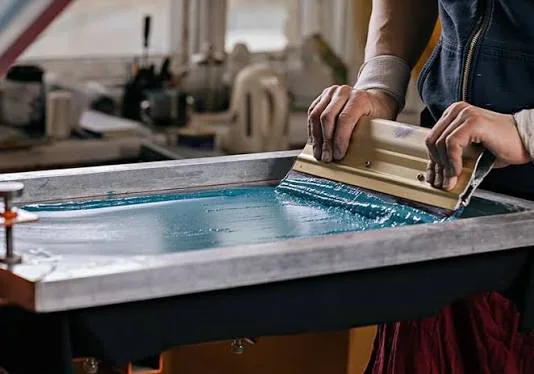 A squeegee pulling thick ink through a screen