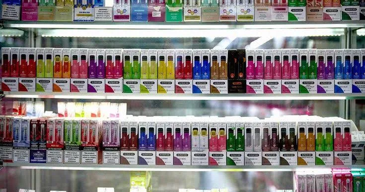 A lit shelf wall of e-liquid bottles in a store