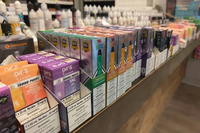 Rows of printed vape cartons on a shop counter rack