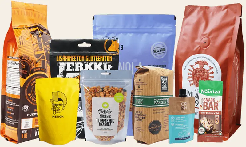 A collection of printed coffee and snack pouches in orange, blue, kraft and yellow