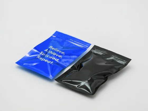Two flat pouches, one blue and one black, lying side by side on a pale surface