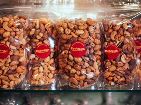 A row of narrow side-gusseted clear pouches filled with nuts on a lit shelf