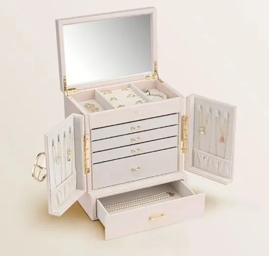 A white jewellery box with a mirrored lid open above tiered drawers of rings