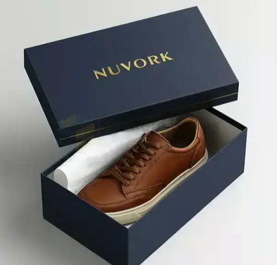 An open navy rigid shoe box with a brown leather shoe resting inside on tissue